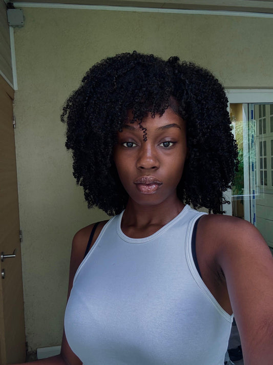 Beautiful Black woman wearing 4C natural coily hair extensions from Amami Antwerp, styled in a voluminous and elegant look.